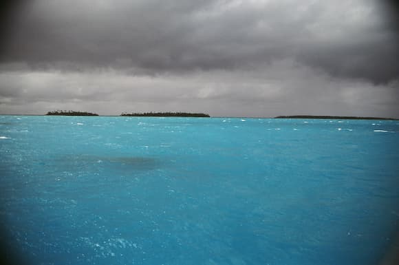 Turquoise lagoon under storm clouds in the Tuamotus