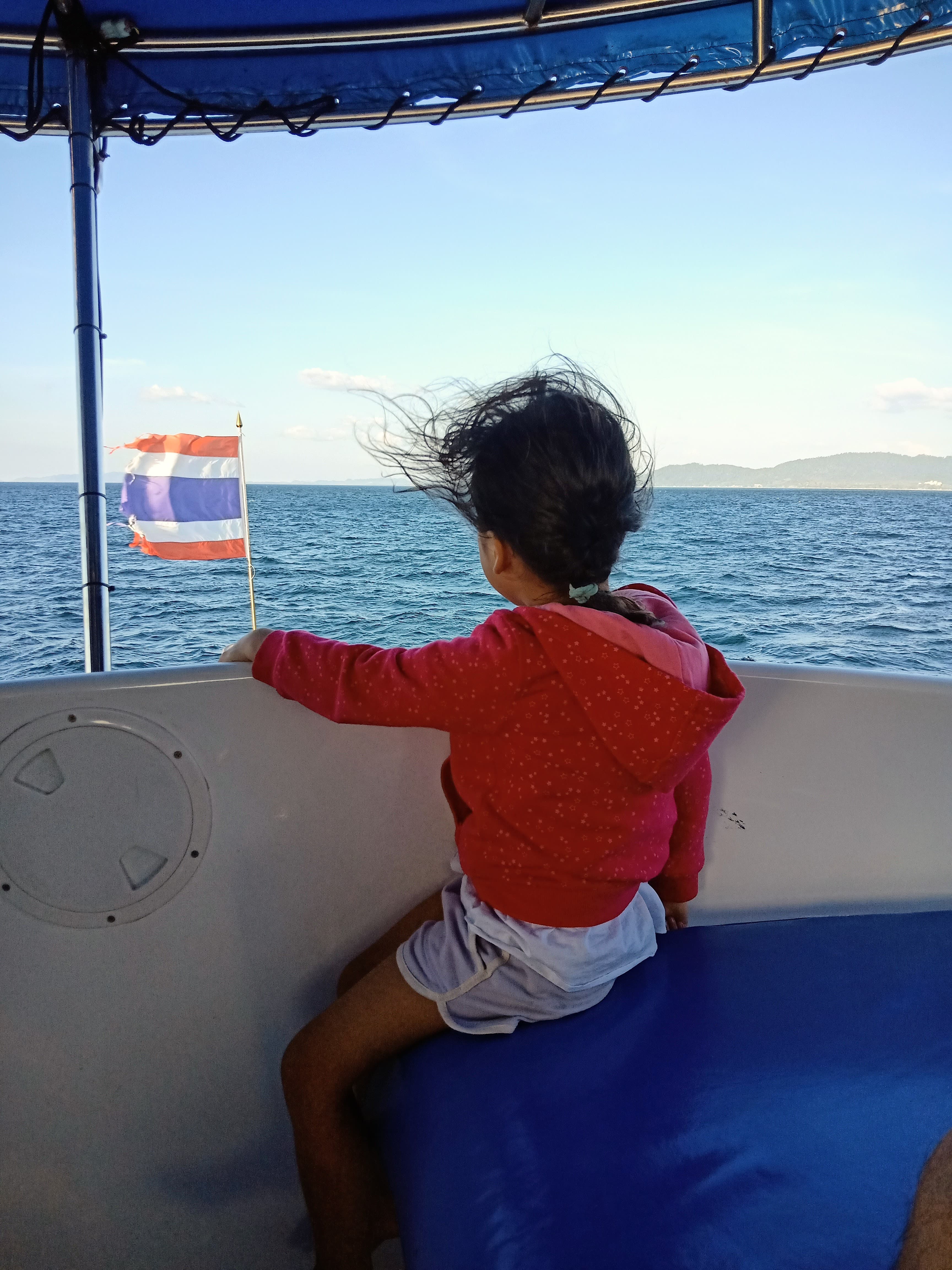Daughter on a boat, wind in her hair, Thai flag flying