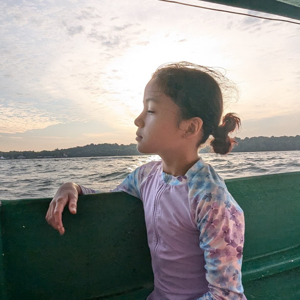 Daughter gazing at the ocean from a boat at sunset